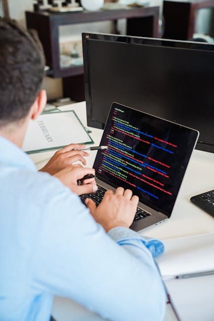 The image displays a close-up of a computer screen with lines of HTML code in various colors, including yellow, blue, green, and red. The code features elements such as headings, image links, classes,